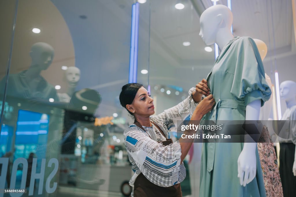 Mujeres indias asiáticas exhiben artista vistiendo maniquí en escaparate de tienda en tienda de ropa femenina