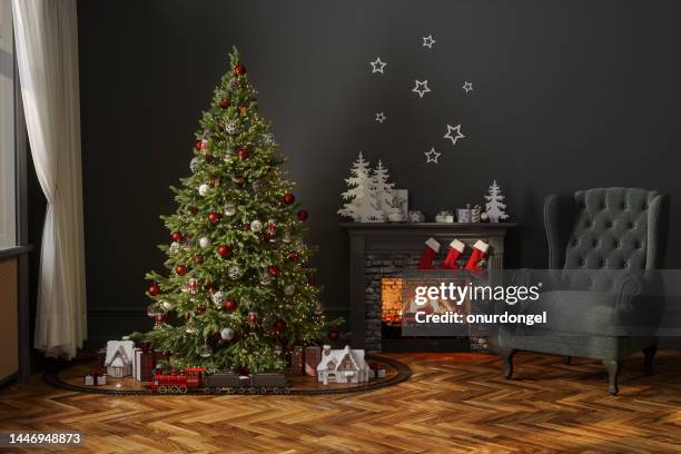 modern living room with christmas tree, miniature train, gift boxes, fireplace and armchair - apartment fire stock pictures, royalty-free photos & images