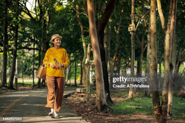 happy woman connection with nature while walking at public park. environmental wellbeing. - sustainable fashion stock pictures, royalty-free photos & images