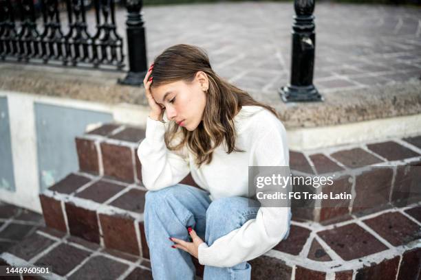 young woman feeling bad outdoors - geestelijke mishandeling stockfoto's en -beelden