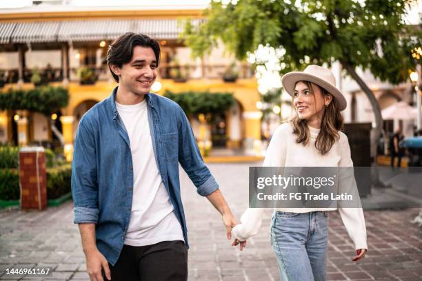 young couple walking together outdoors - young couple holding hands stock pictures, royalty-free photos & images