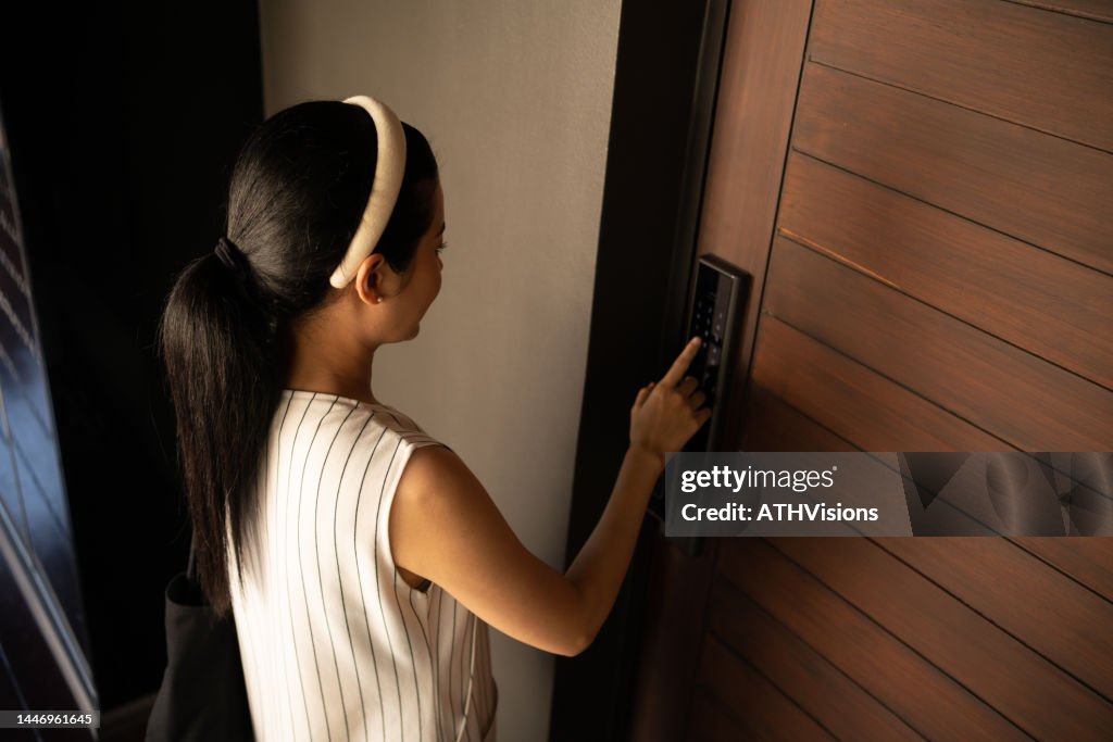 Mulher pressionando o controle de acesso eletrônico para destrancar uma casa de porta