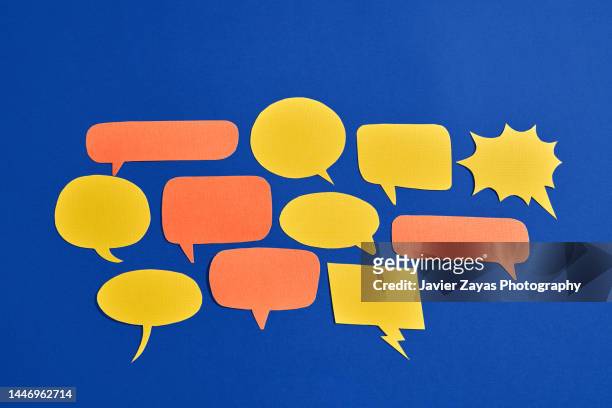 many orange and yellow comic bubbles on blue background - speech bubble imagens e fotografias de stock
