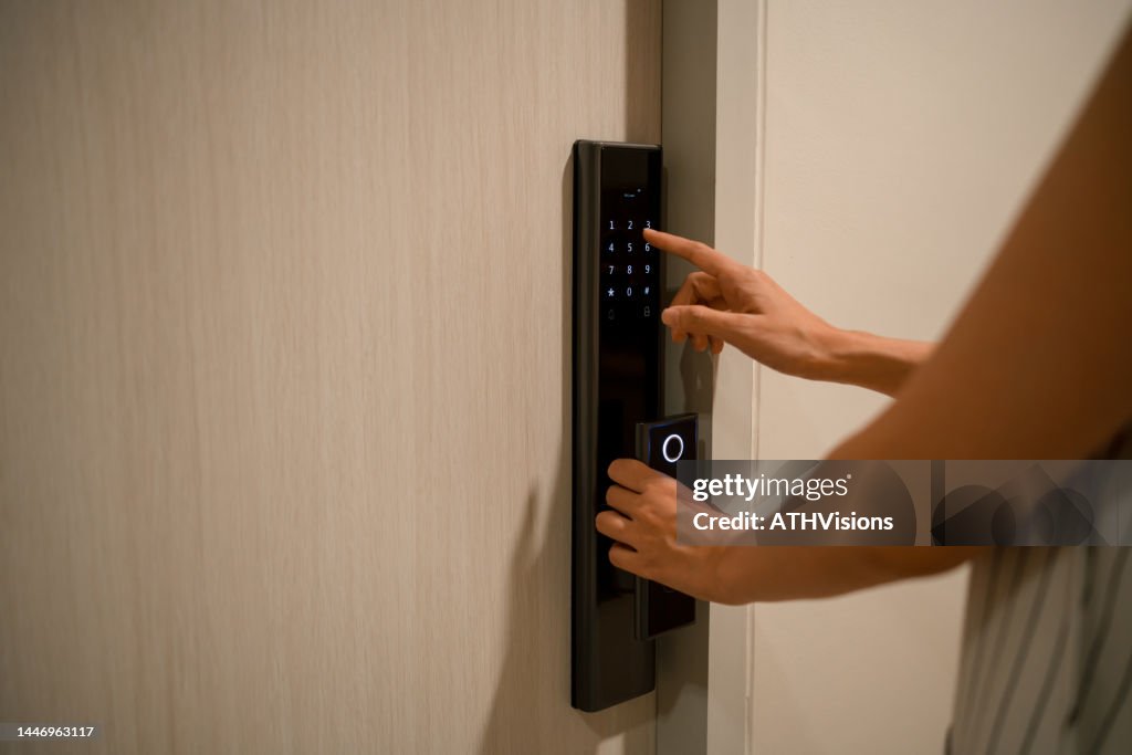 Mulher Pressionando uma senha no controle de acesso eletrônico para desbloquear uma sala de porta em casa