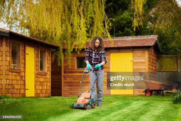 female gardener mowing the lawn - gräsklippare bildbanksfoton och bilder