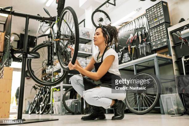 young female bicycle mechanic working on a bicycle - bicycle shop 個照片及圖片檔