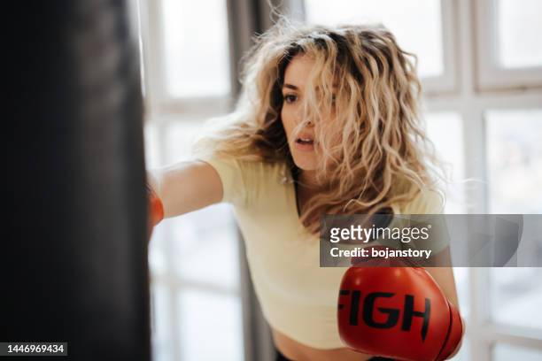 young female boxer training with punching bag in the gym - woman gym boxing stockfoto's en -beelden