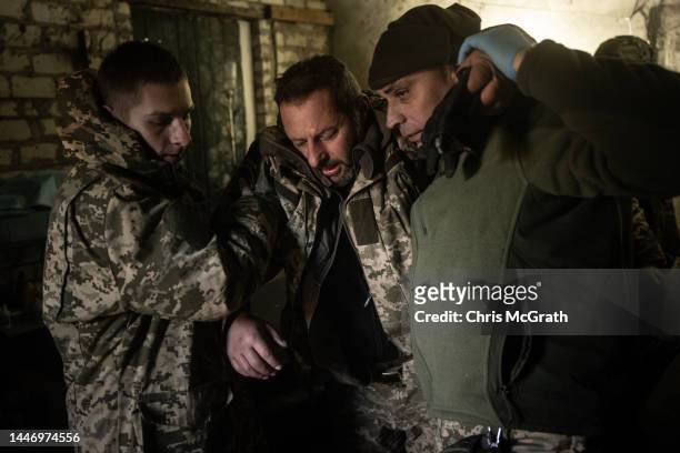 Military medics assist a member of the Ukrainian military suffering from concussion to a ambulance at a frontline field hospital on December 05, 2022...