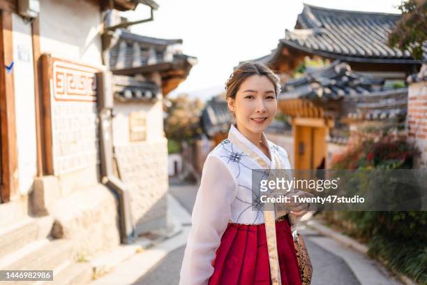 cheerful asian woman wearing korean hanbok traditional dress traveling in bukchon hanok village - korean culture fotografías e imágenes de stock