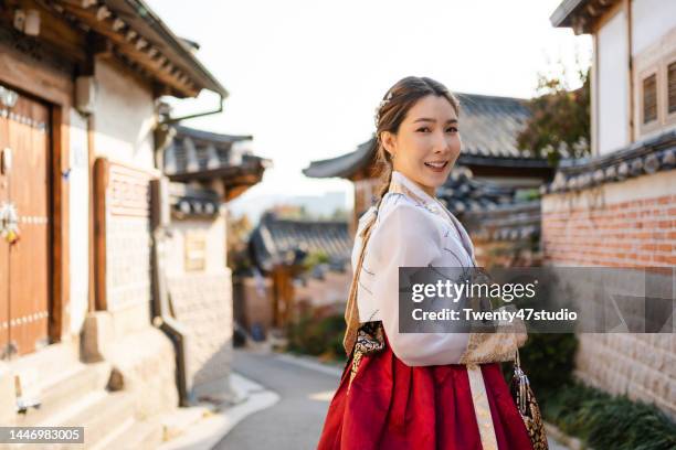 cheerful asian woman wearing korean hanbok traditional dress traveling in bukchon hanok village - korean culture photos et images de collection