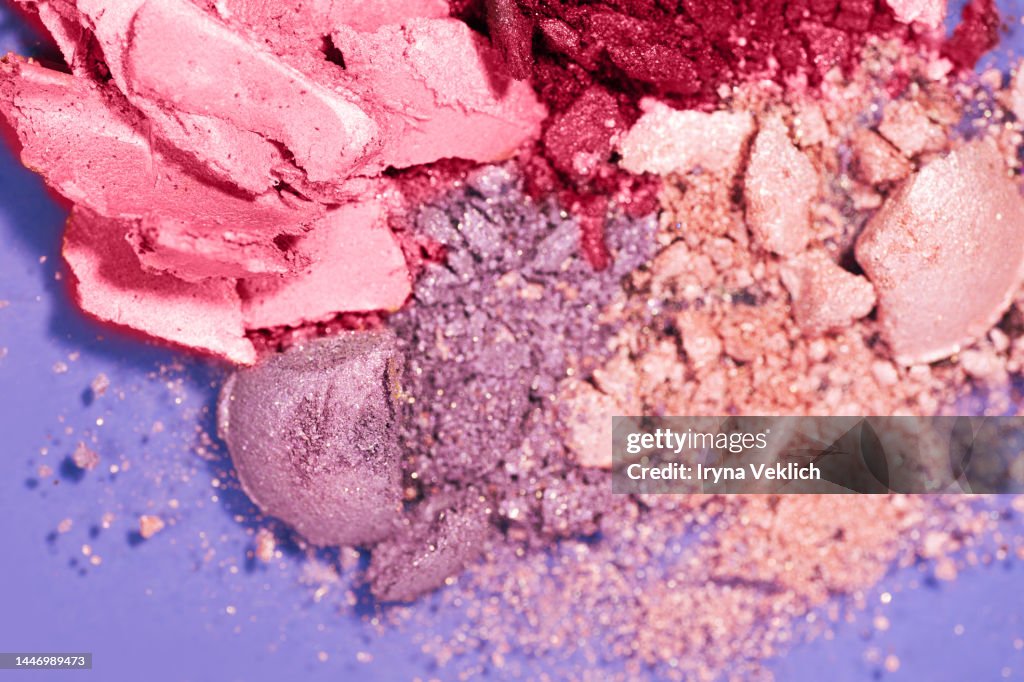 Cosmetic Make-up product for a woman - eyeshadow in powder in pink and Red Viva Magenta Color of The Year 2023 on pastel Violet color background.