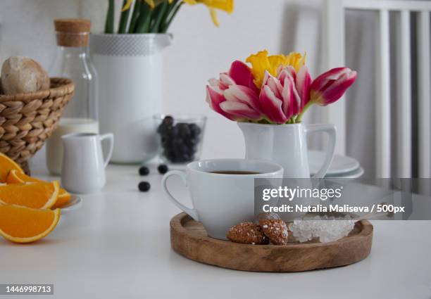 a cup of coffee and a vase with tulips and daffodils on a wooden stand - quality daffodils stock pictures, royalty-free photos & images