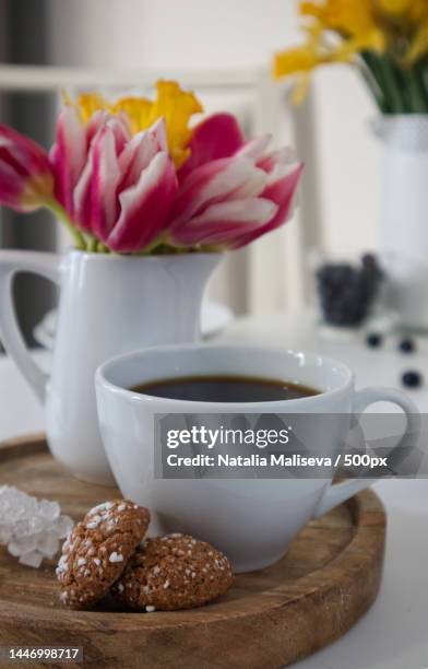 a cup of coffee and a vase with tulips and daffodils on a wooden stand - quality daffodils stock pictures, royalty-free photos & images