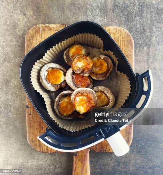 stuffed mushrooms in air fryer on wooden cutting board on brown background - airfryer stock pictures, royalty-free photos & images
