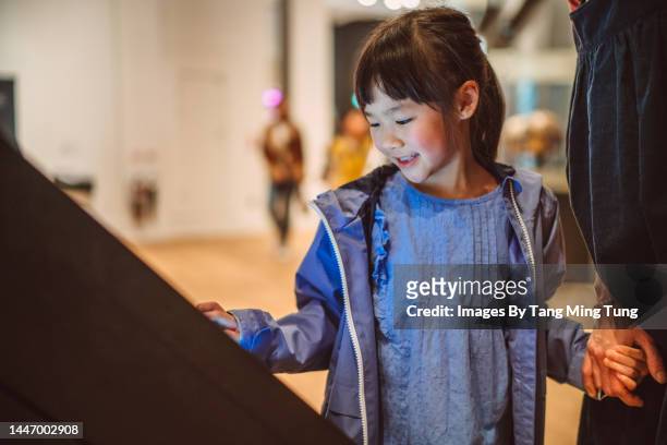 lovely cheerful girl checking out exhibits with interactive touch screen in art gallery - adult entertainment expo stockfoto's en -beelden