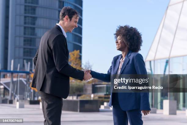 two office colleagues greeting by shaking hands, multi ethnic business people, black ethnic businessman and businesswoman outside at work, busy colleagues - staff bonding stock pictures, royalty-free photos & images