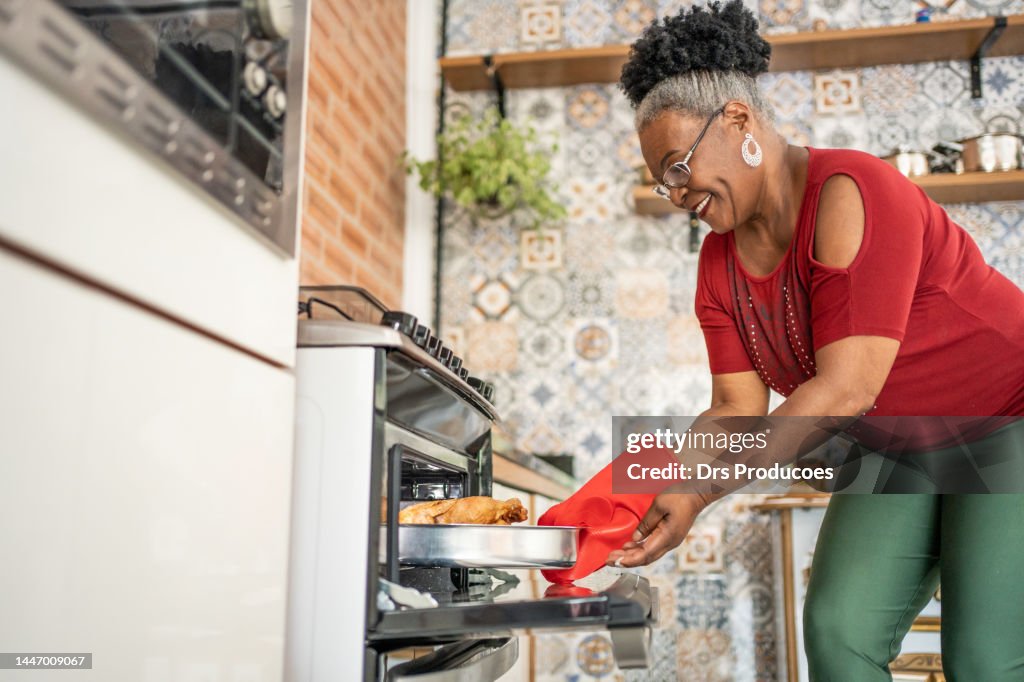 Mulher madura que tira o peru de Natal do forno