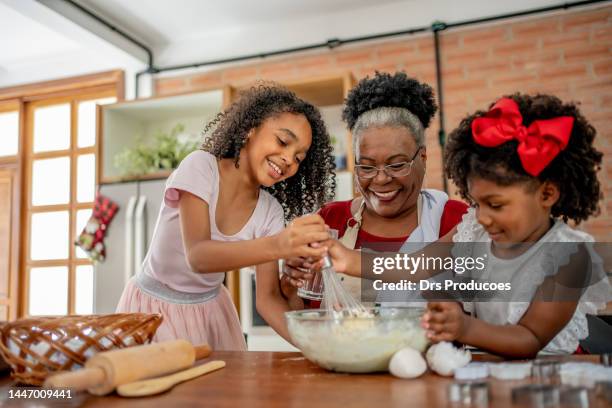 grand-mère et petites-filles faisant des biscuits de noël - kids cooking christmas photos et images de collection