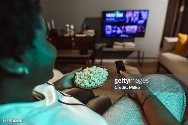 donna afro-americana che guarda il programma televisivo preferito e mangia popcorn a casa. pov - glee - tv show foto e immagini stock