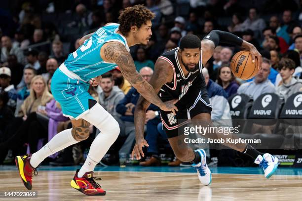 Paul George of the LA Clippers brings the ball up court while guarded by Kelly Oubre Jr. #12 of the Charlotte Hornets in the second quarter during...