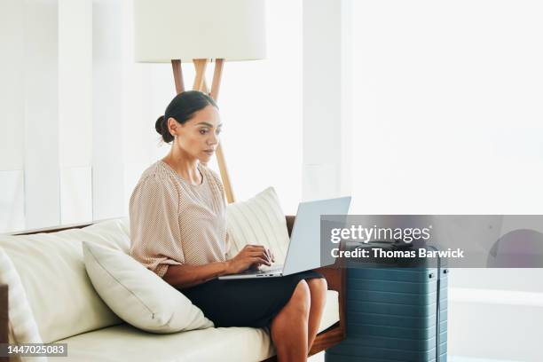 wide shot of businesswoman working on laptop in hotel lobby - premium acess stock pictures, royalty-free photos & images