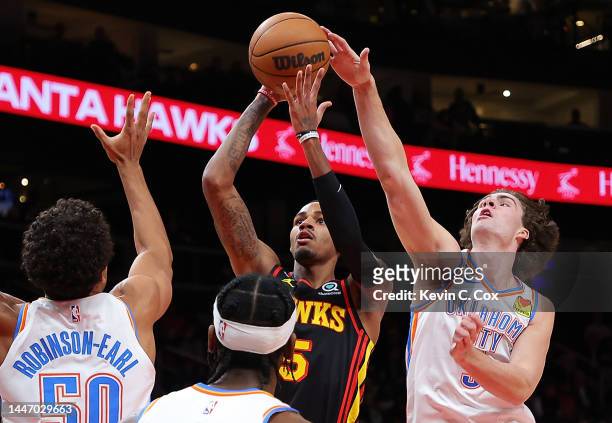 Josh Giddey of the Oklahoma City Thunder blocks a shot by Dejounte Murray of the Atlanta Hawks during the first half at State Farm Arena on December...