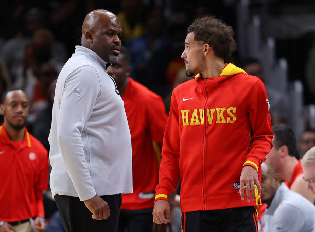 Trae Young walks past head coach Nate McMillan of the Atlanta Hawks to re-enter the game against the Oklahoma City Thunder during the second half at...