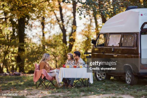 happy family talking during autumn picnic at trailer park. - family caravan stock pictures, royalty-free photos & images