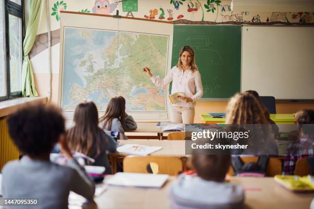 female teacher teaching geography at elementary school. - students map imagens e fotografias de stock