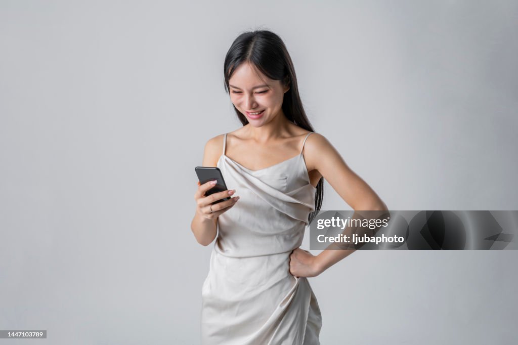 Junges hübsches Mädchen, das im Stehen ein Smartphone benutzt.