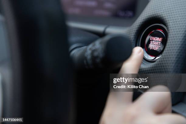 close-up of woman hand reaching for engine start button in a car - pulsante di attivazione o disattivazione foto e immagini stock
