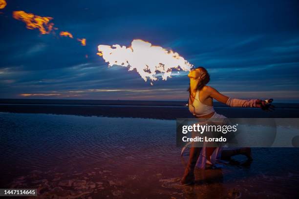 beautiful brunette female fire eater on the beach at night - fire dancer stock pictures, royalty-free photos & images