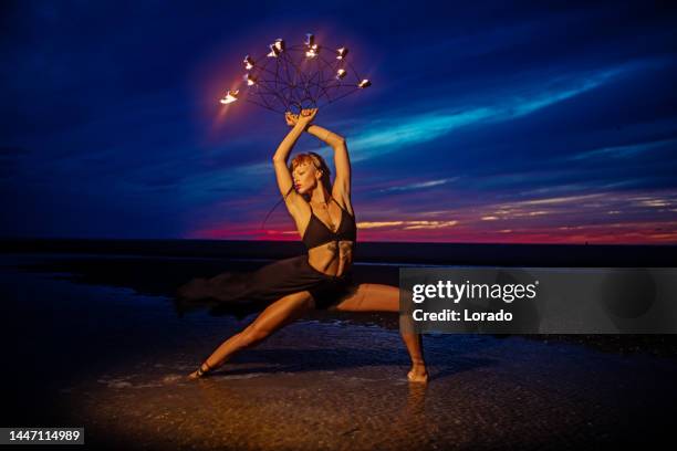 beautiful brunette female fire dancer on the beach at night - fire performer stock pictures, royalty-free photos & images