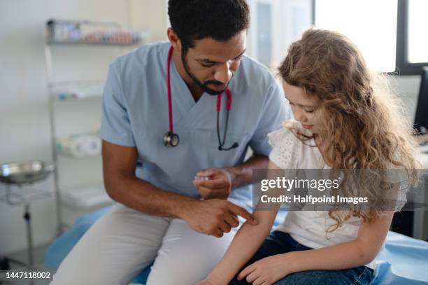 young doctor preparing little girl for taking blood. - gesundheitsvorsorge stock-fotos und bilder