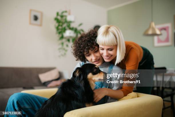 happy couple of lovers relaxing at home with their pet dog - gay couple stock pictures, royalty-free photos & images