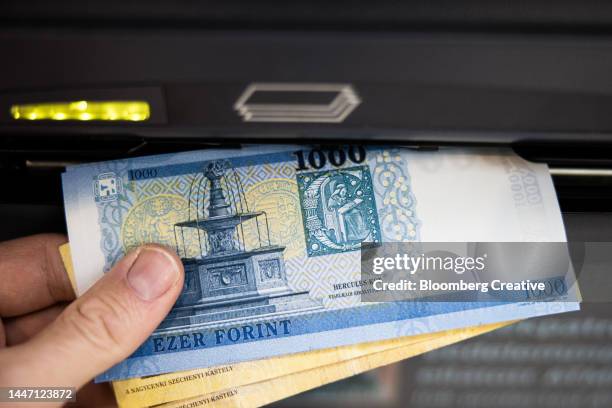 a person withdraws hungarian banknotes from a cash machine - hungary forint stock pictures, royalty-free photos & images