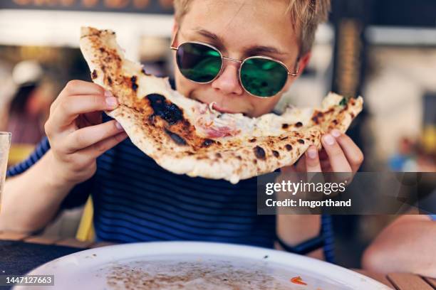 teenage boy enjoying eating pizza very much. - pizzeria bildbanksfoton och bilder