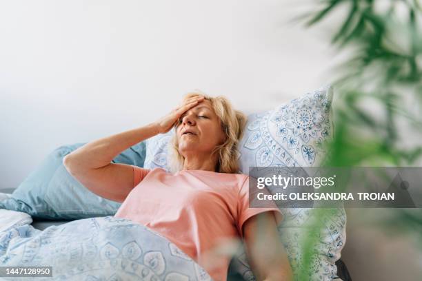 middle aged woman having hot flashes in bed - ホルモン ストックフォトと画像