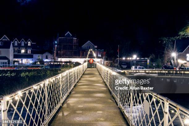 christmas lights on pedestrian footbridge in lynmouth. - exmoor national park night stock pictures, royalty-free photos & images