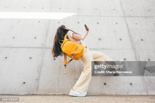 happy young woman jumping against wall. - vestito giallo foto e immagini stock