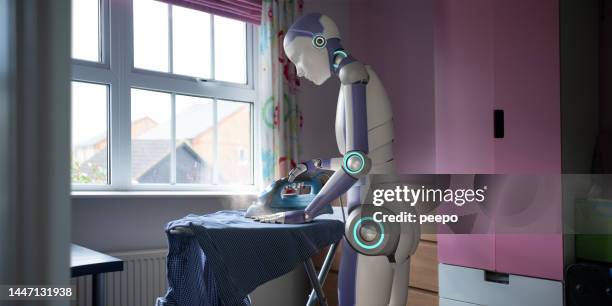 domestic robot ironing laundry in the home - house cleaning stock pictures, royalty-free photos & images