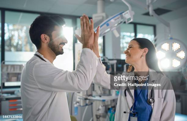 young doctor giving high five with his colleague in operating gown at hospital. - dallas texas hospital stock-fotos und bilder