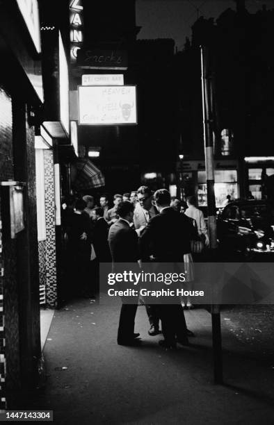 Pedestrians and groups of people outside the Heaven & Hell Coffee Lounge and 2i's Coffee Bar on Old Compton Street in the Soho area of the West End...
