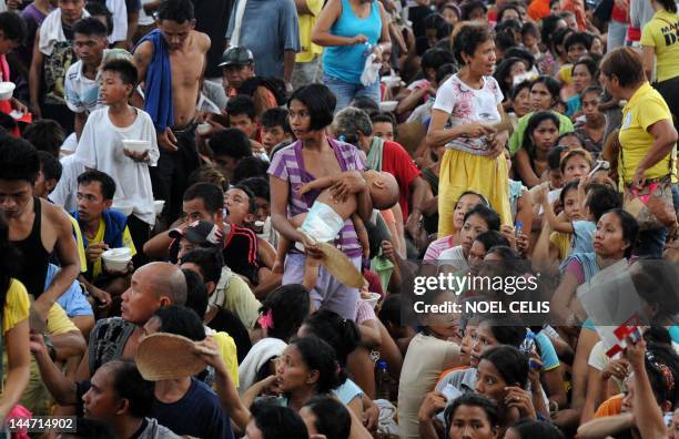 Victims of a fire queue up for relief items provided by the Philippine National Red Cross at the Delpan Sports complex in Manila on May 18, 2012....