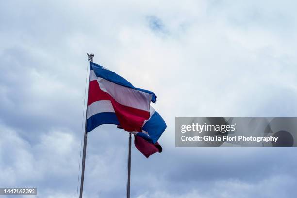 costa rican flag against a cloudy sky - costa rica flag stock pictures, royalty-free photos & images