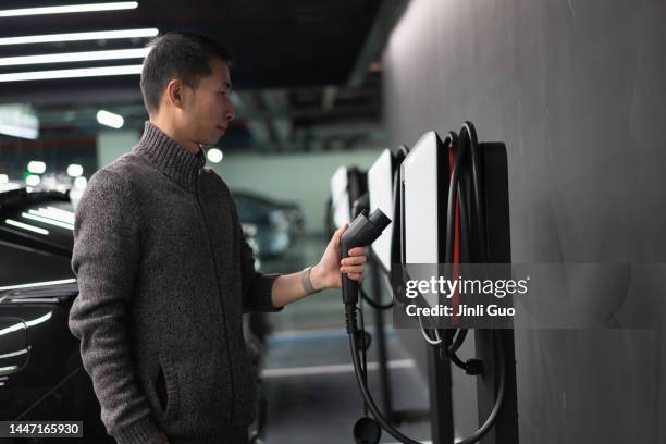 man is preparing to charge electric car - battery charger stock pictures, royalty-free photos & images