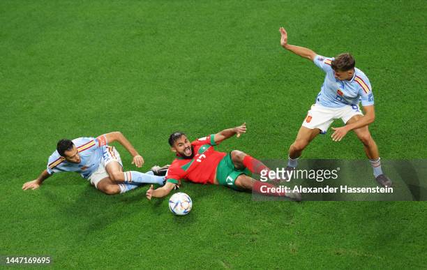 Sofiane Boufal of Morocco battles for possession with Sergio Busquets and Marcos Llorente of Spain during the FIFA World Cup Qatar 2022 Round of 16...