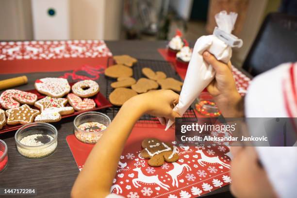 a cropped rear shot of a boy decorating a gingerbread man - gingerbread biscuit stock pictures, royalty-free photos & images