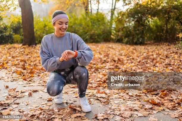une jeune femme vérifie son activité physique sur une montre intelligente après avoir fait du jogging dans le parc - podomètre photos et images de collection