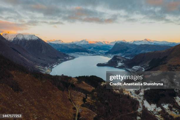 luftaufnahme der dramatischen straße zum see mit schneebedecktem bergblick während des wintersonnenuntergangs in norwegen - more stock-fotos und bilder